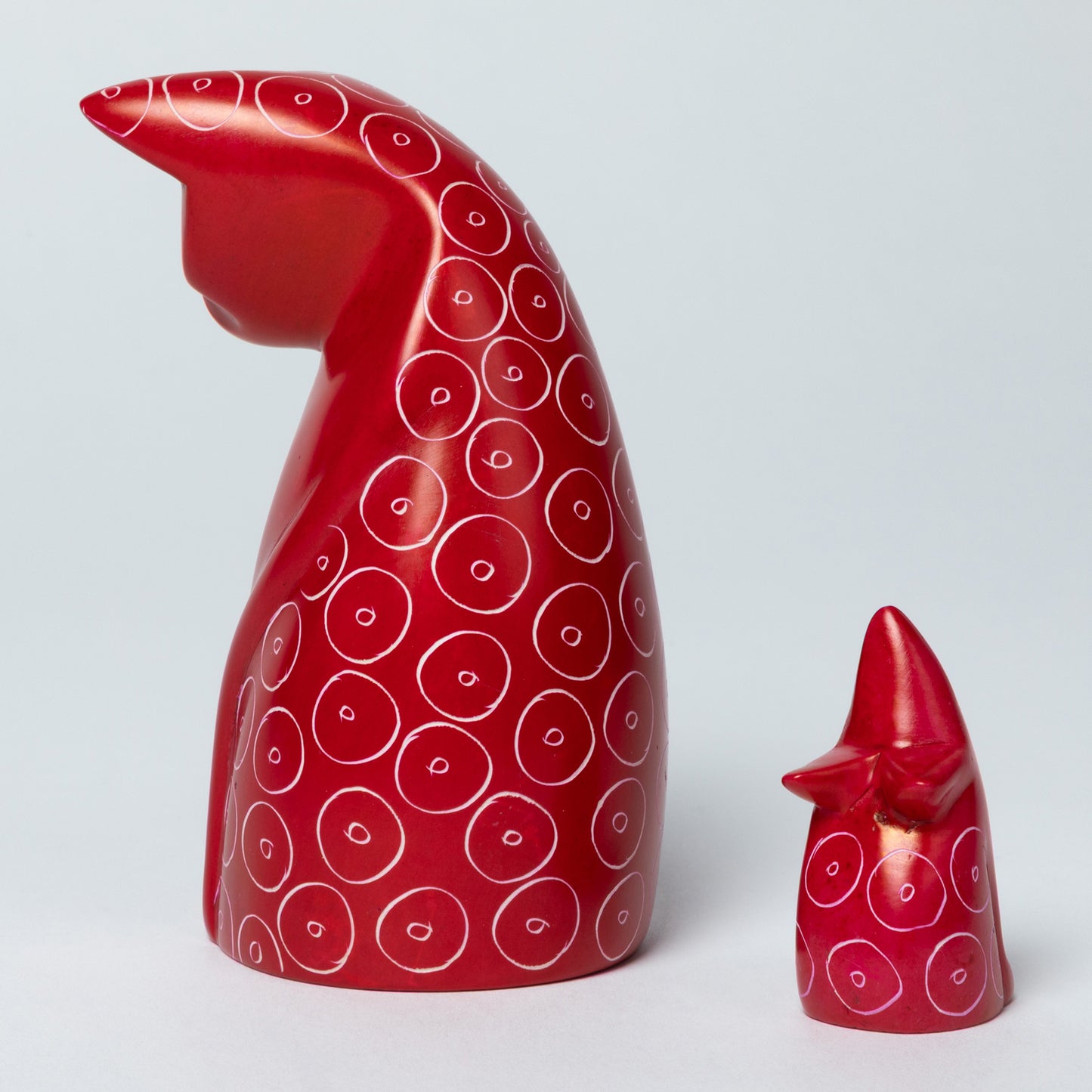 Red soapstone cat and mouse figurines with white circular patterns on a white background