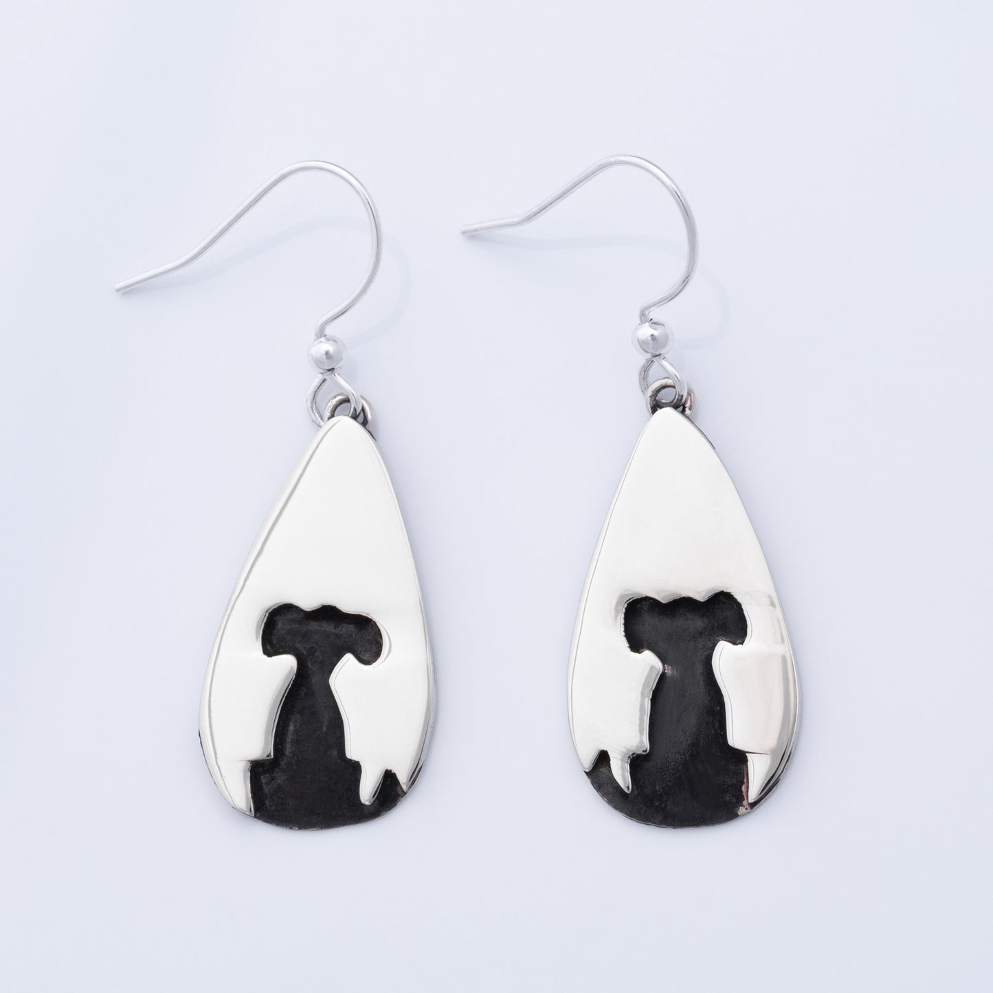 Teardrop-shaped earrings with black and white designs on a light gray background