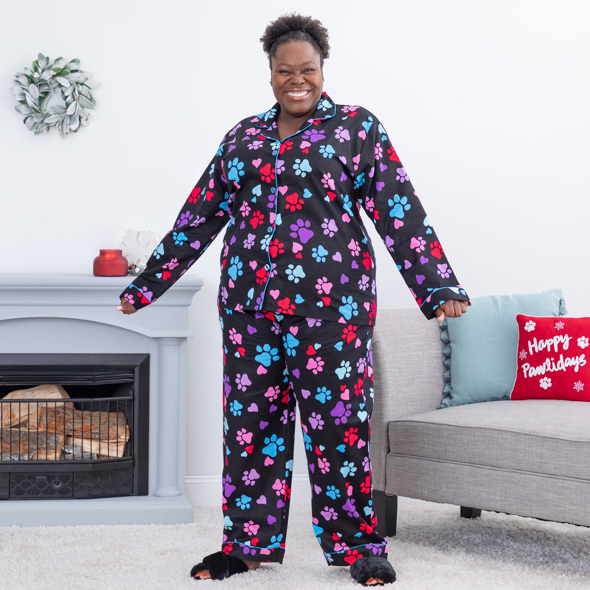 Smiling woman in colorful paw-print pajamas stands in a cozy living room.