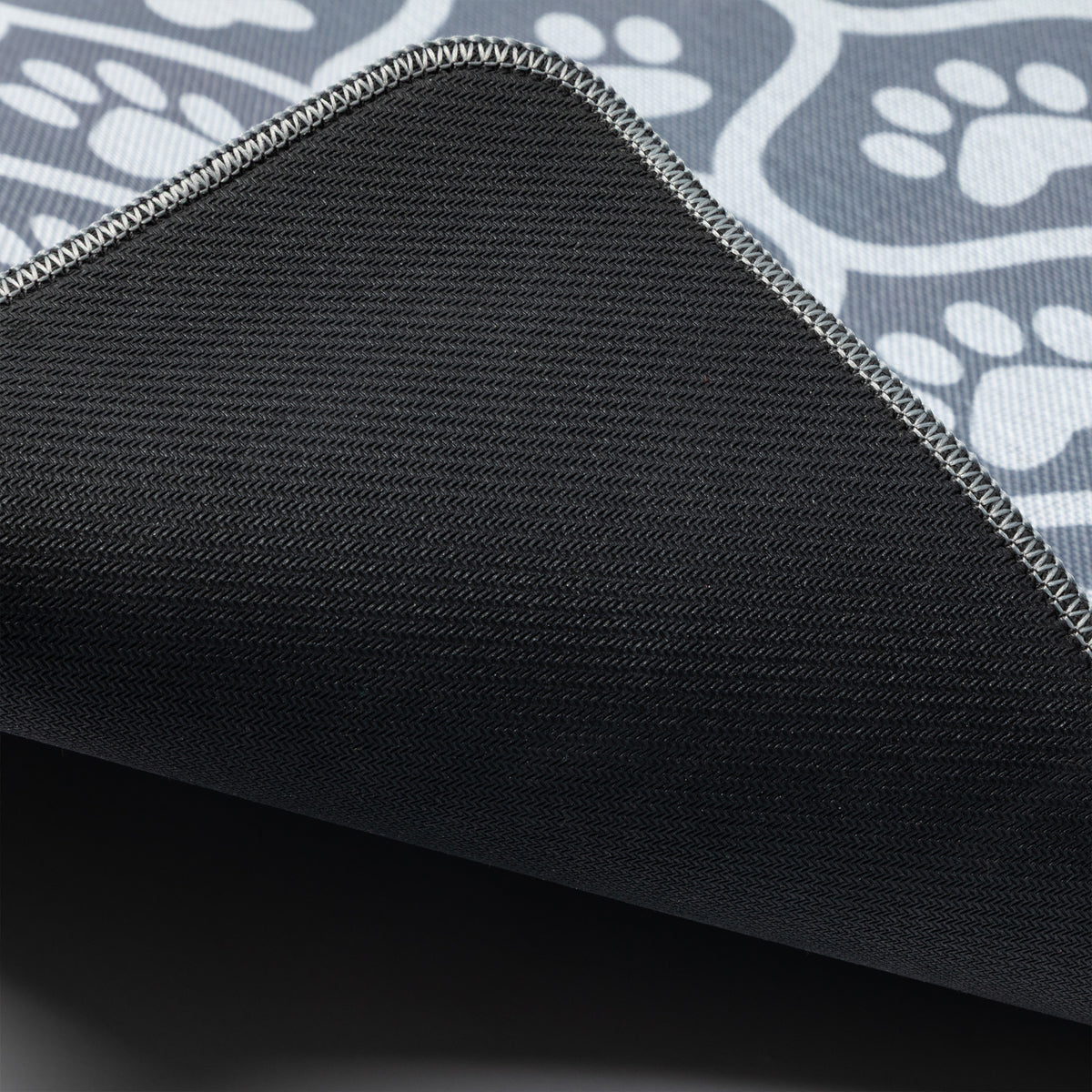 Close-up of the textured black nonslip backing on a floor mat with a patterned gray and white upper.
