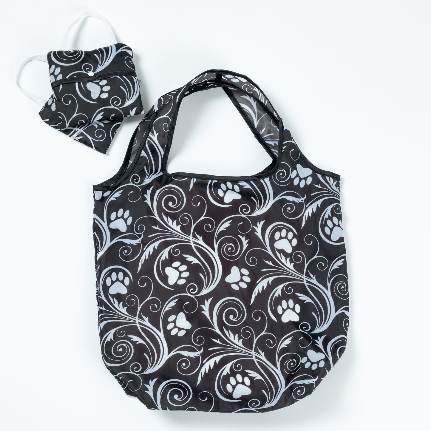 A set of three reusable shopping bags with paw print and animal-themed patterns, displayed alongside their compact storage pouch.