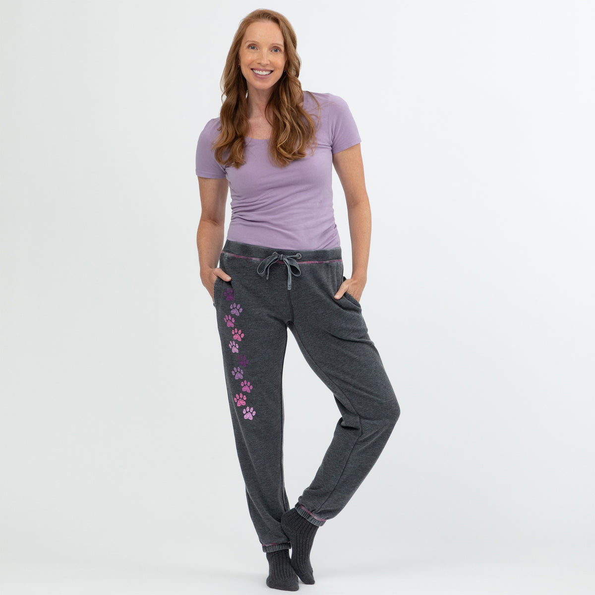 Woman wearing a purple shirt and gray pants with paw prints on a white background