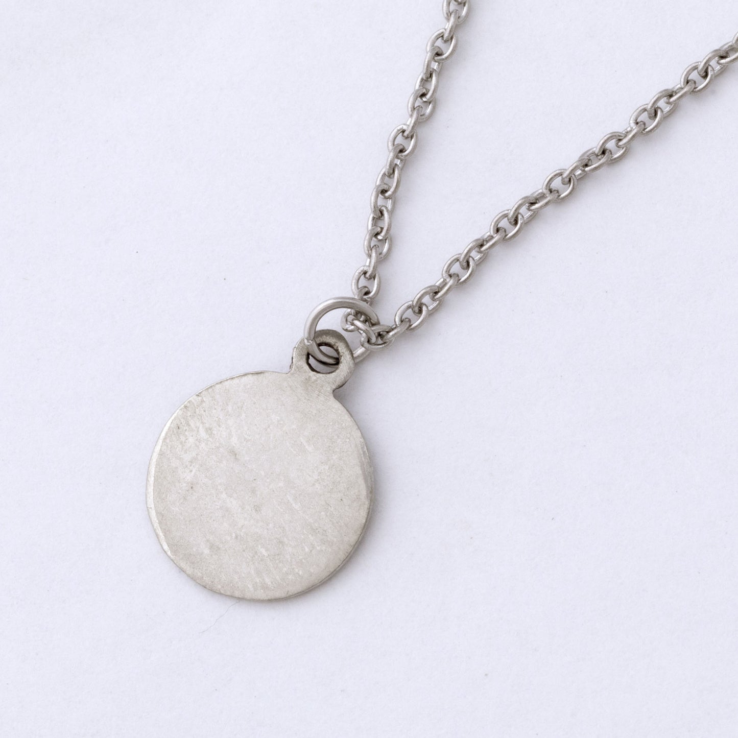 Silver necklace with a round pendant on a white background