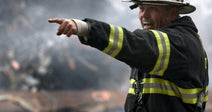 On the left, an FDNY deputy chief in turnout gear points urgently amid smoking rubble; on the right, a rescue worker with a search dog navigates debris-strewn streets.