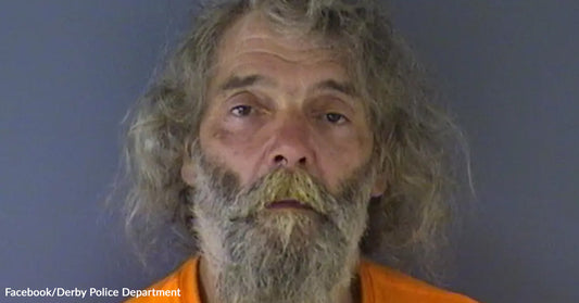 Mugshot of an older man with long gray hair and a beard wearing an orange shirt.
