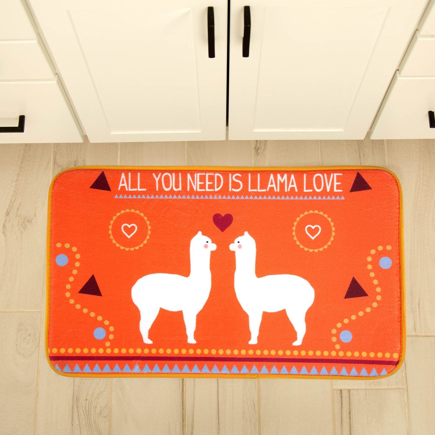 Orange rug with llamas and the phrase 'All you need is llama love' on a wooden floor.