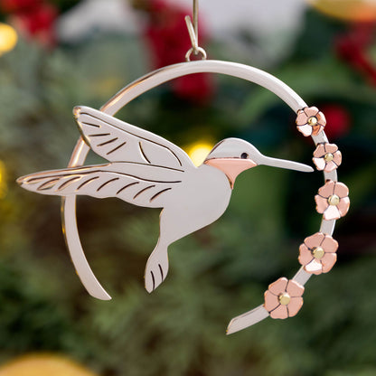 Decorative ornament of a hummingbird with floral design on a Christmas tree.