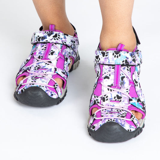 Colorful purple and black sandals with unique paw print design on a person’s feet.