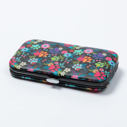 A rectangular manicure kit with a colorful floral and paw print pattern on a black background, featuring a silver metal clasp, photographed on a light gray studio background.