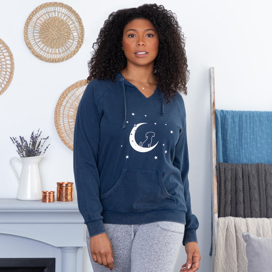 Woman wearing a navy hoodie with a moon and stars design, posing indoors.