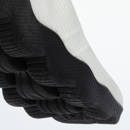 Close up of deep traction sole on a white stretchy shoe upper with a white background