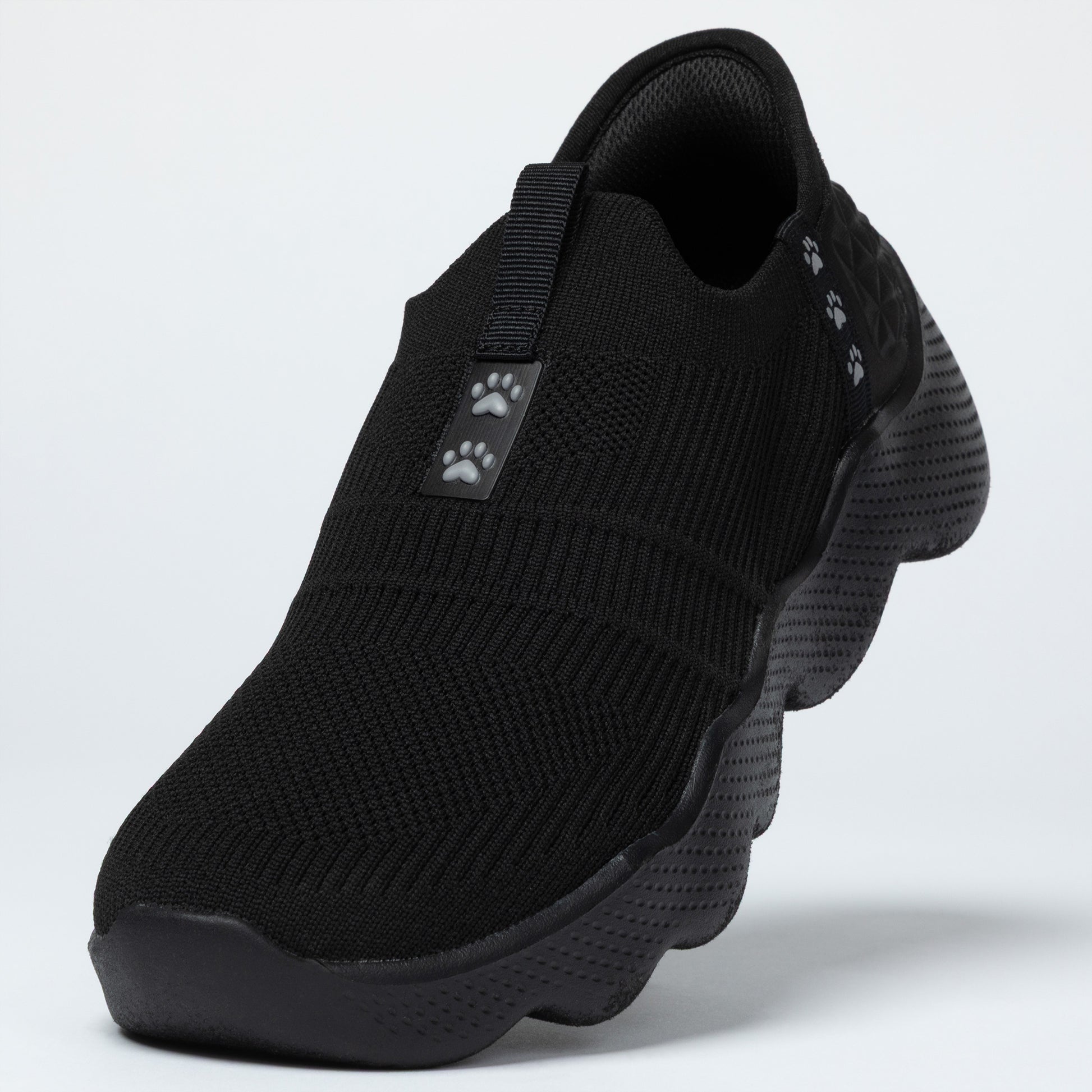 Black slip-on shoe with paw print design on a light gray background