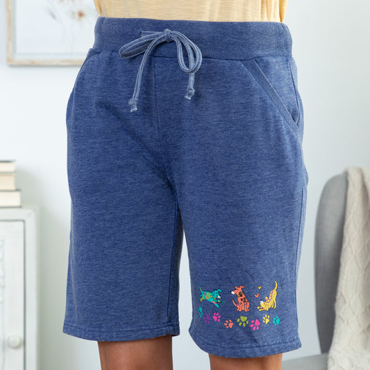 A pair of blue board shorts with a pattern of colorful cartoon dogs.