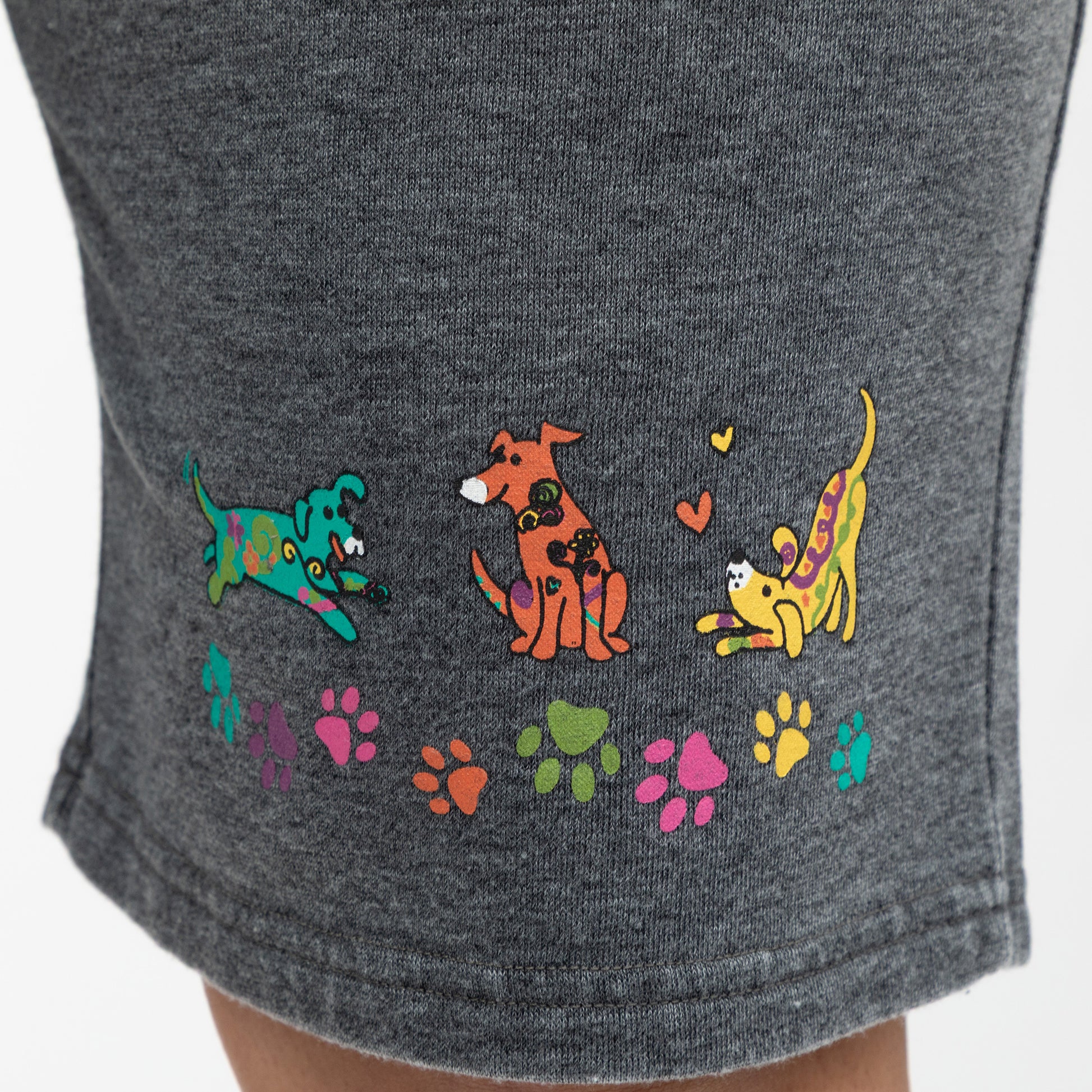 Gray shorts with colorful dog illustrations and paw prints on a white background