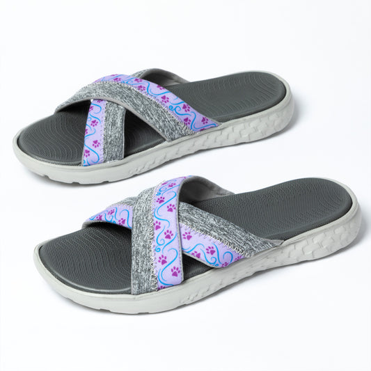 A pair of slide sandals with gray straps featuring a multicolor paw print pattern, against a white background.