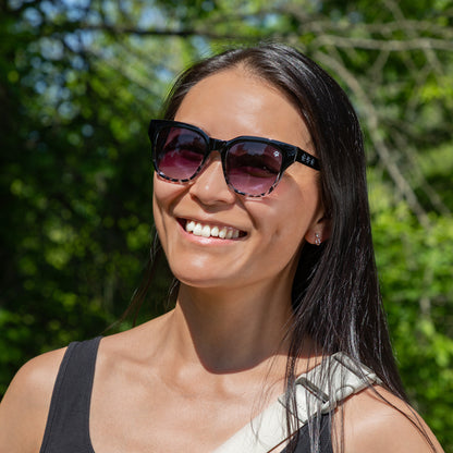 Woman wearing sunglasses with a blurred green background