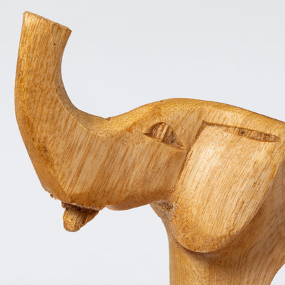 Close up of a wooden elephant carved into a napkin ring on a white background.