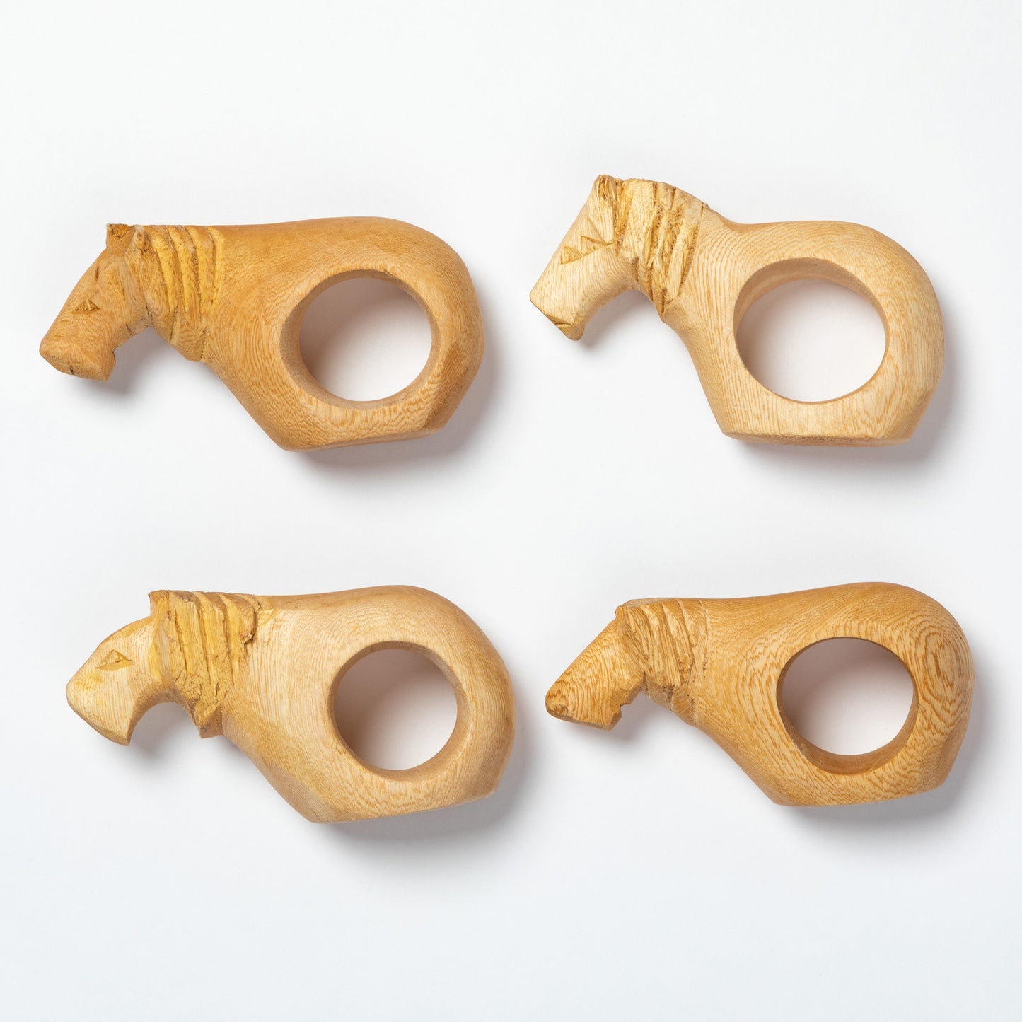 Four wooden napkin rings shaped like animals on a white background