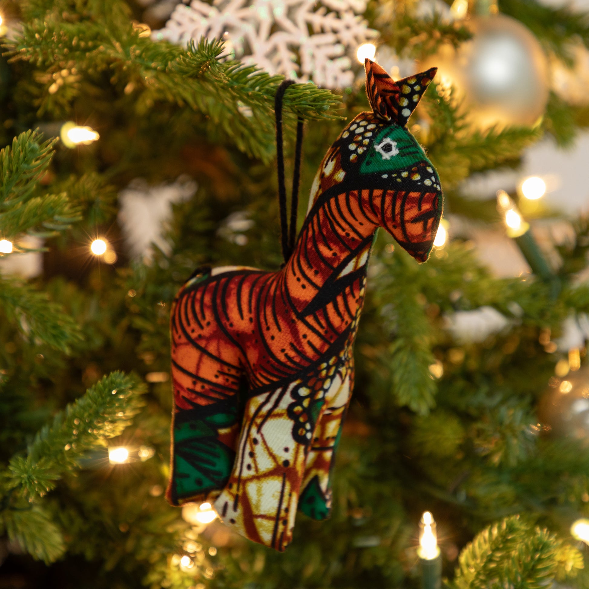 Colorful zebra ornament hanging on a decorated Christmas tree.
