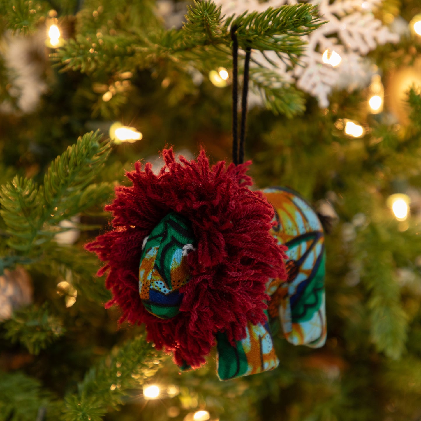 Decorative Lion Christmas ornament with a colorful design hanging on a tree.