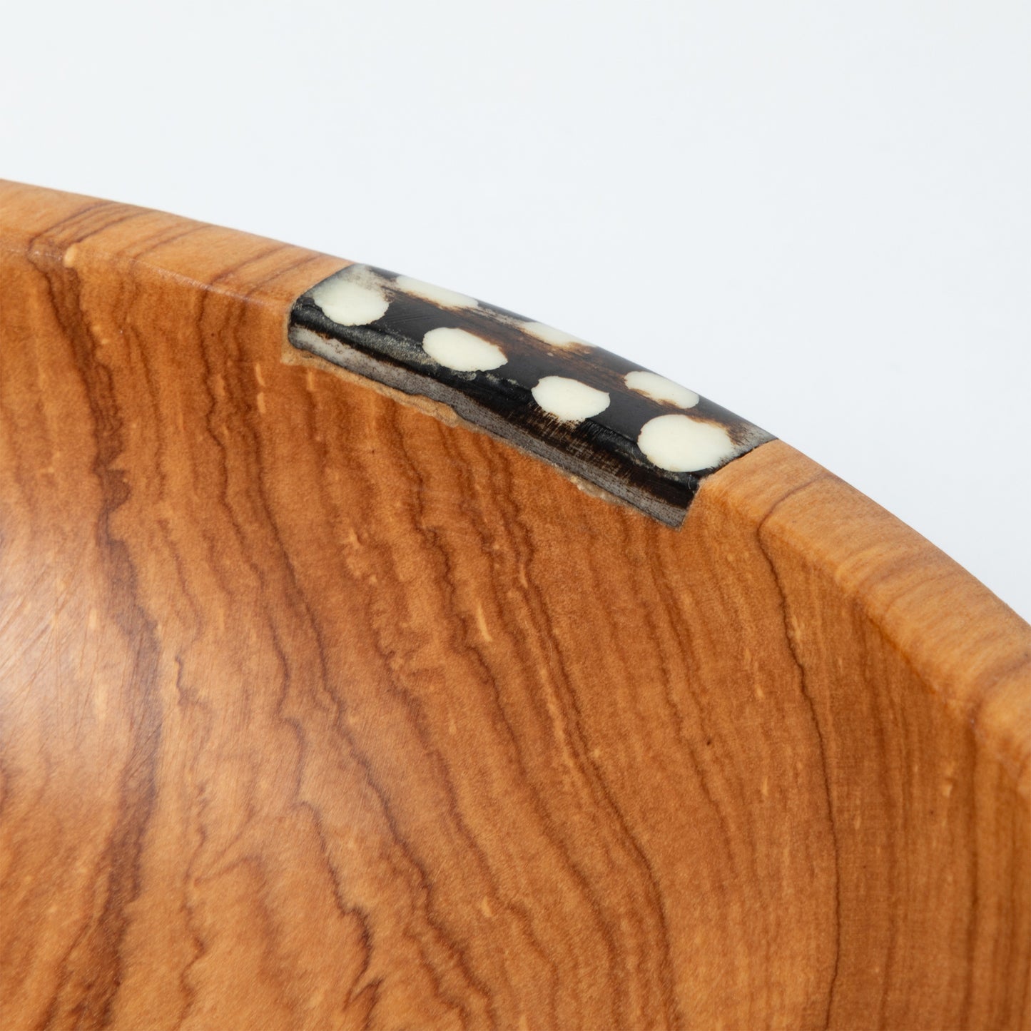 Close-up of a wooden bowl with a visible grain pattern on a white background