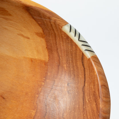 Wooden bowl with a decorative bone accent on a white background