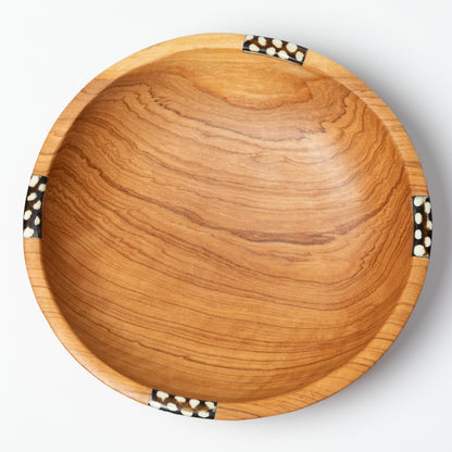 Wooden bowl with a decorative bone accent on a white background