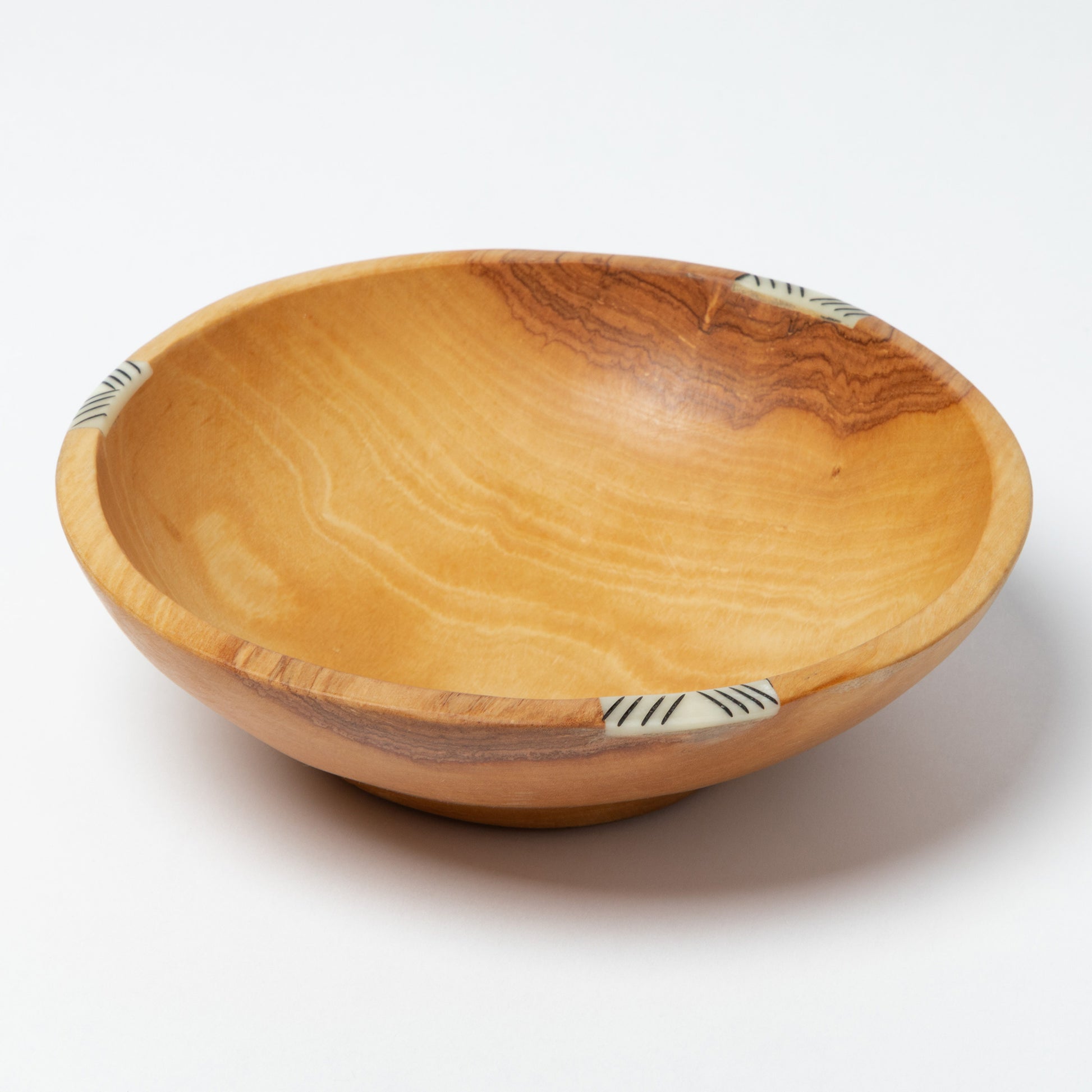 Wooden bowl with decorative bone inlay on a white background