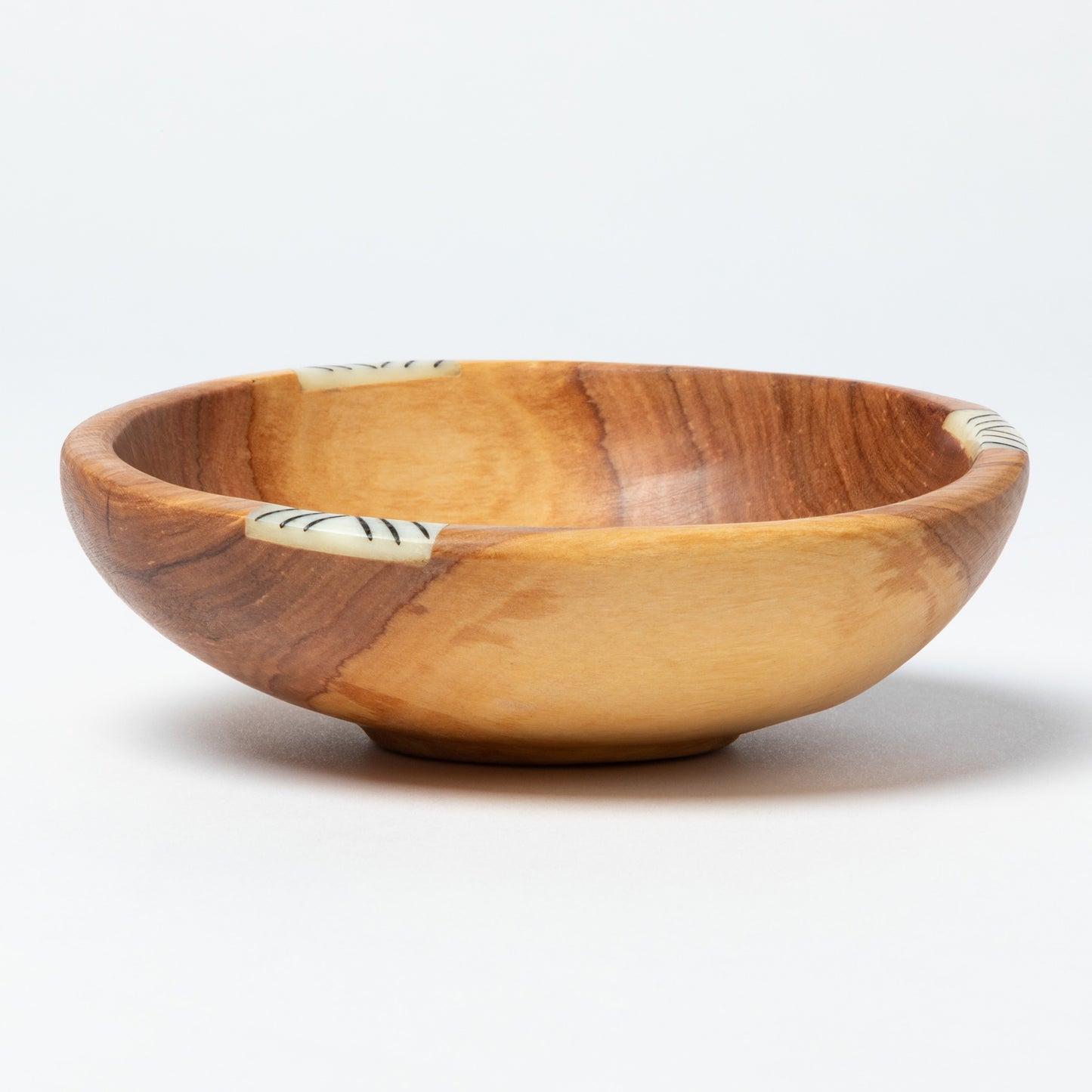 Wooden bowl with small bone inlay on a white background
