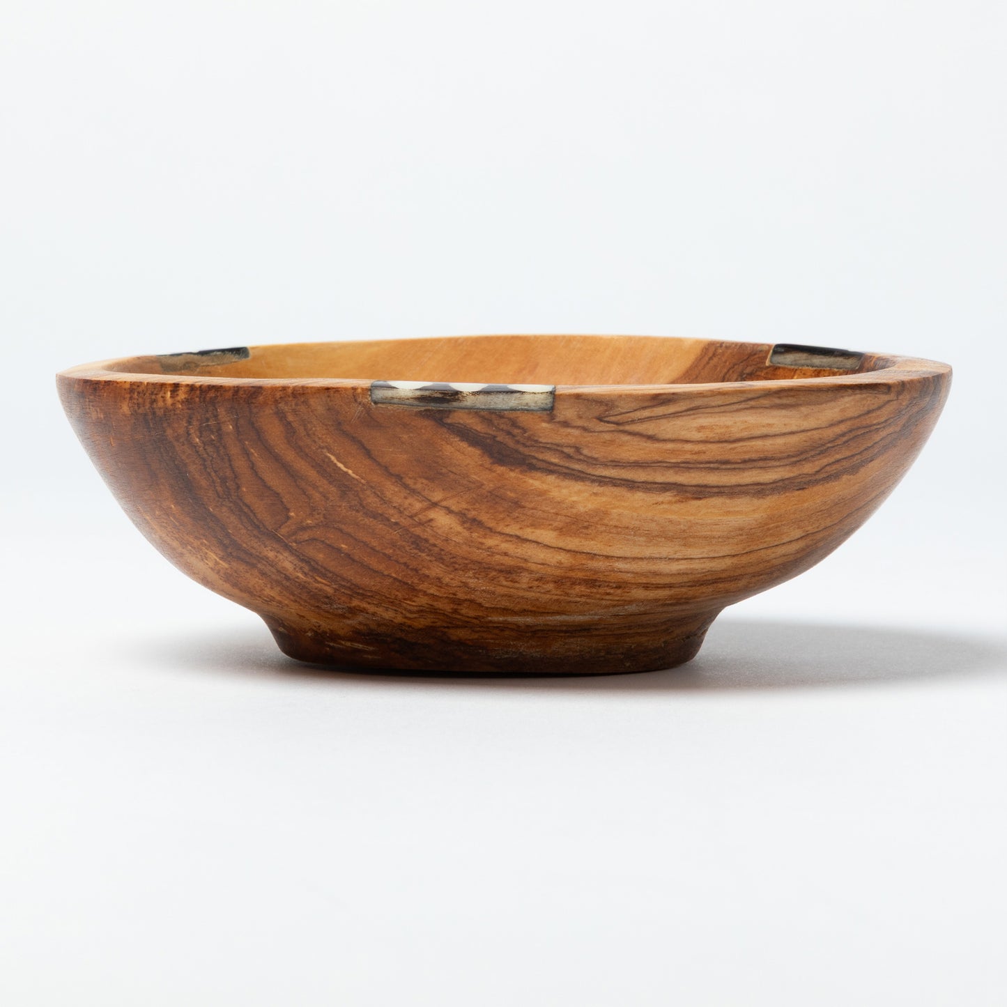 Wooden bowl with a decorative bone accent on a white background