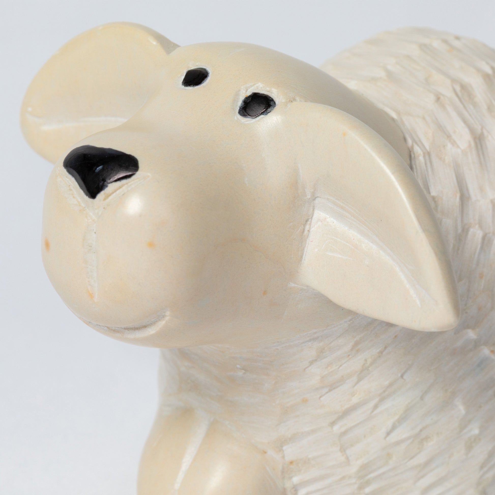 Close-up of a soapstone sheep figurine on a light gray background