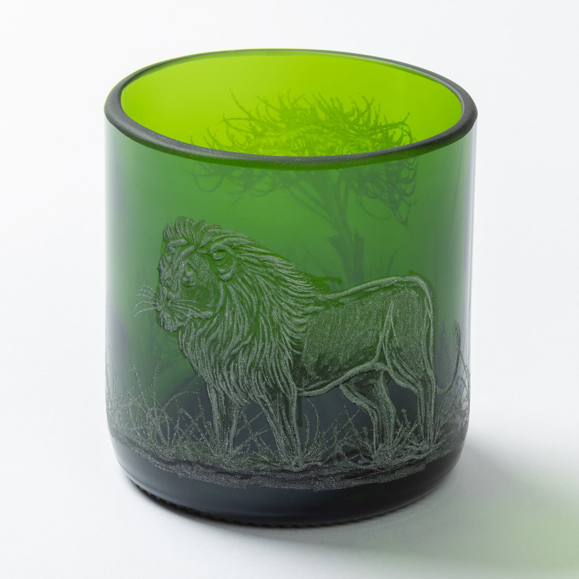 Green glass tumbler with a lion engraving on a white background
