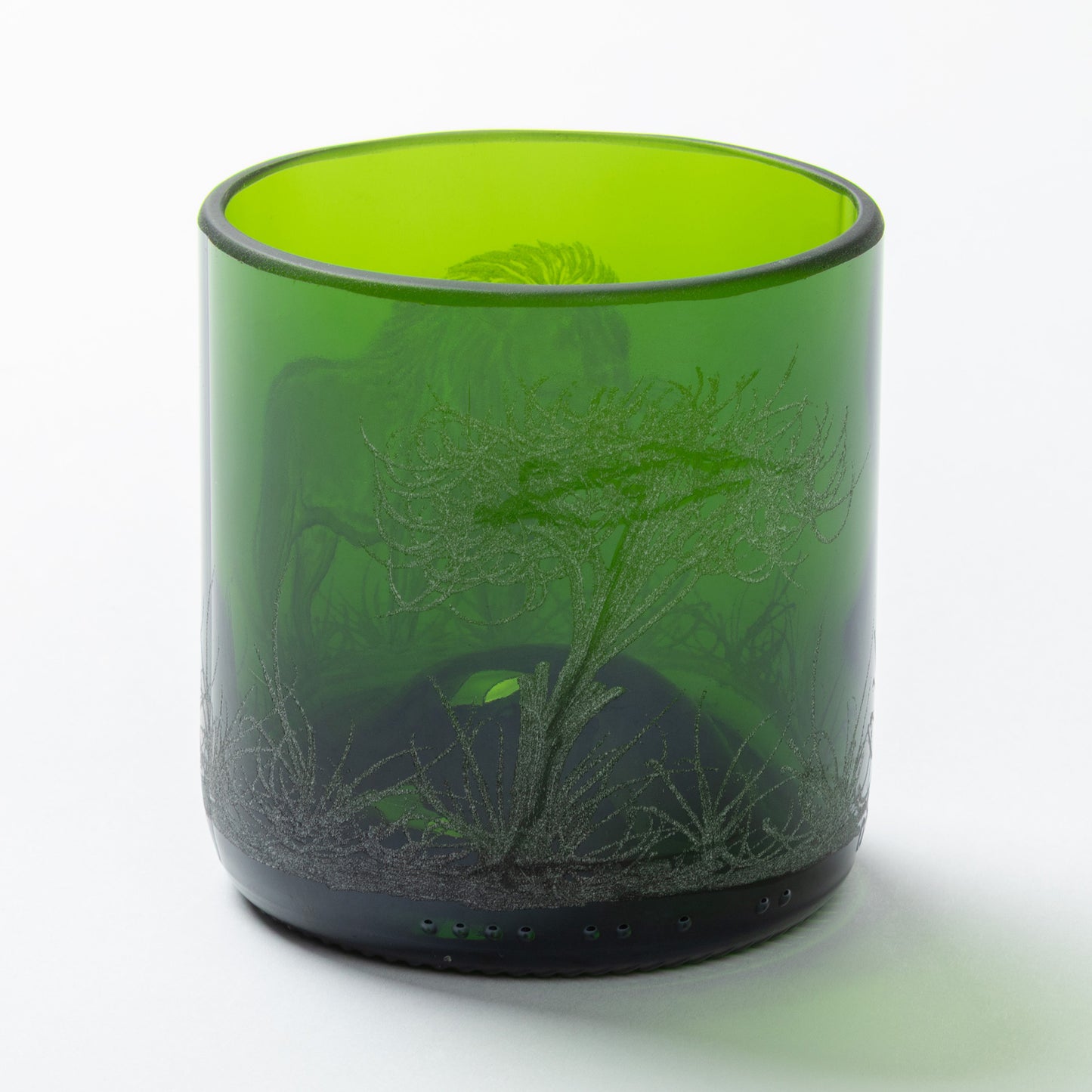 Green glass tumbler with engraved design on a white background
