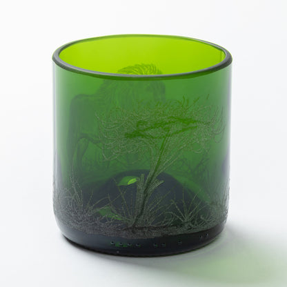 Green glass tumbler with engraved design on a white background