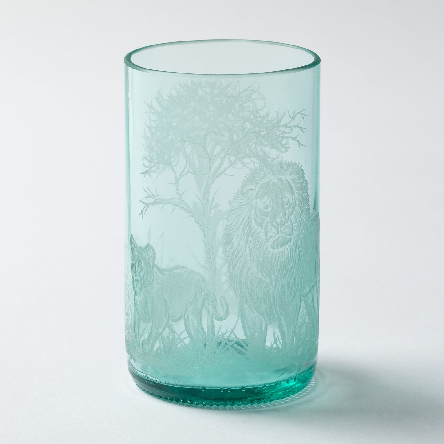 Turquoise glass tumbler with animal etching on a white background
