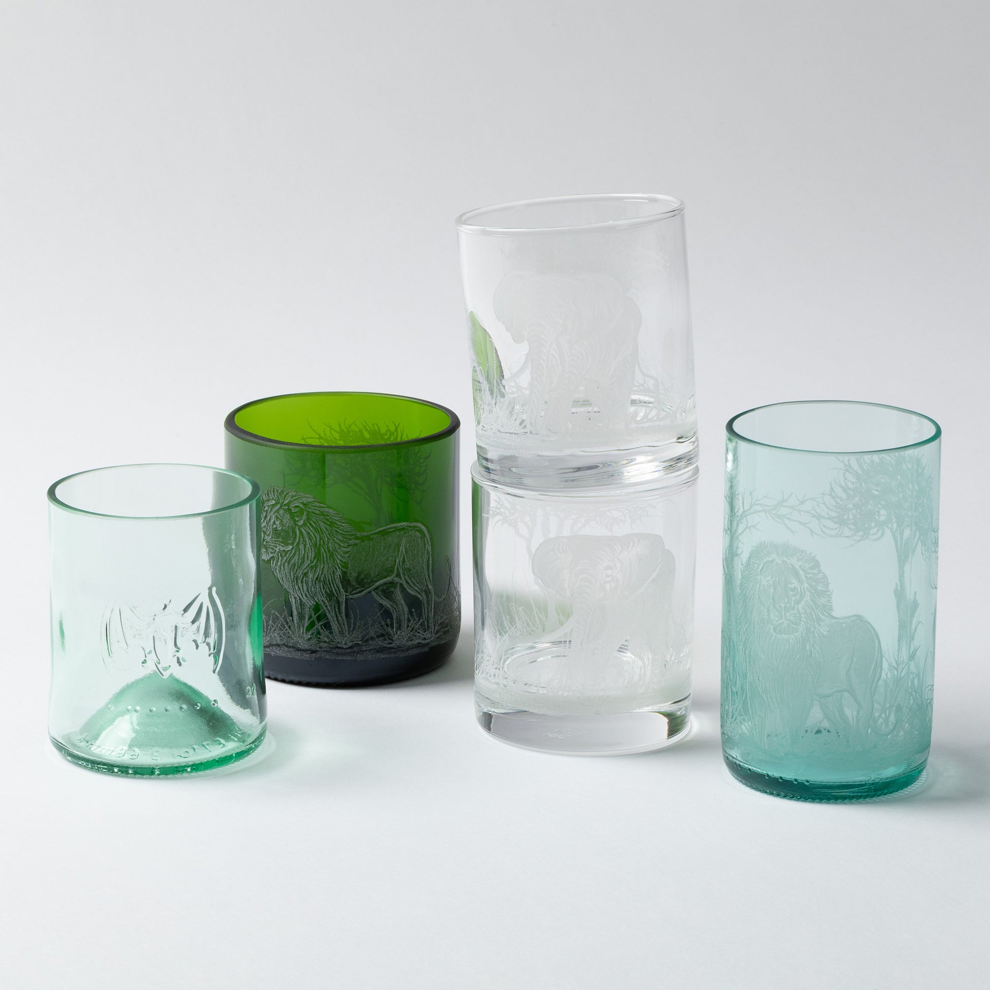 Four glass tumblers in different colors on a white background