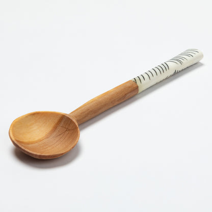 Wooden spoon with a patterned bone accent handle on a white background