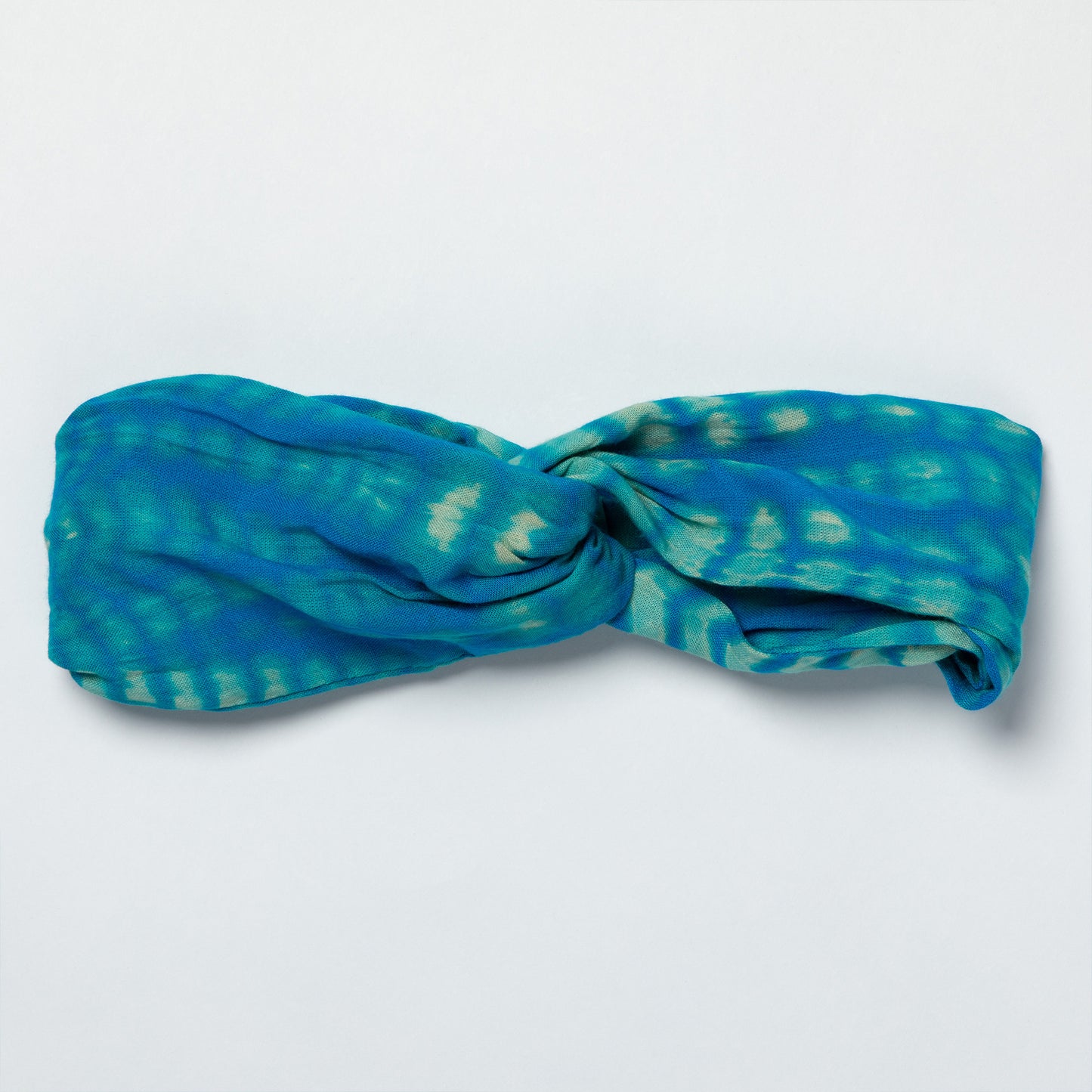 Blue and green patterned headband on a light gray background