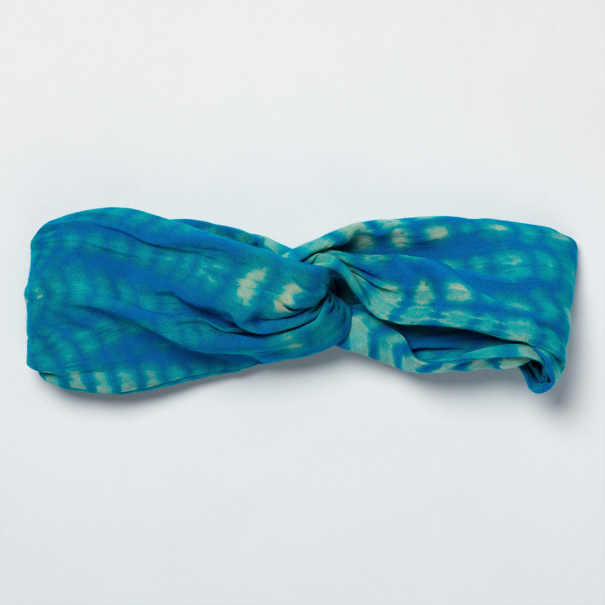 Blue and green patterned headband on a light gray background