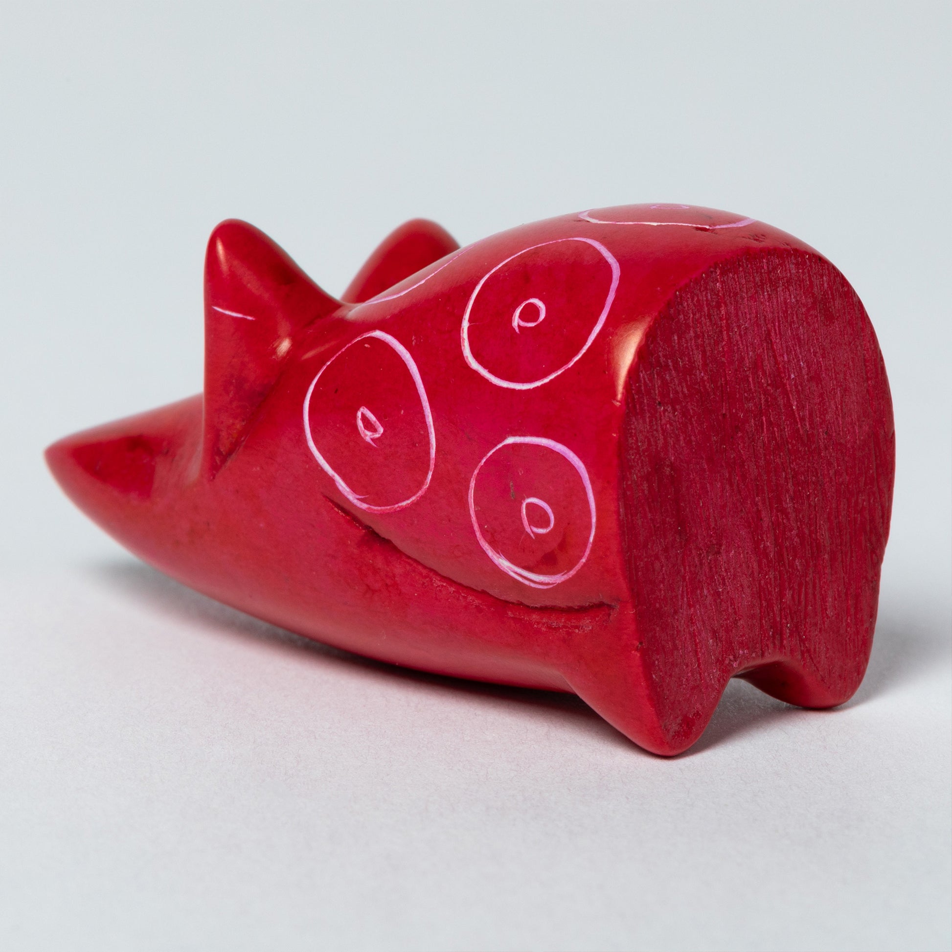Red soapstone mouse figurine with white circular patterns on a white background