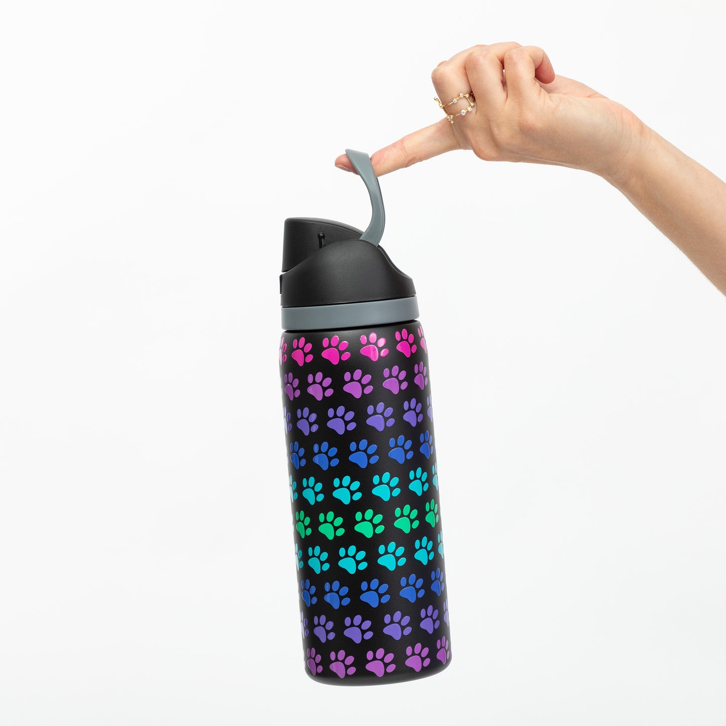 Water bottle with colorful paw pattern held by a hand on a white background