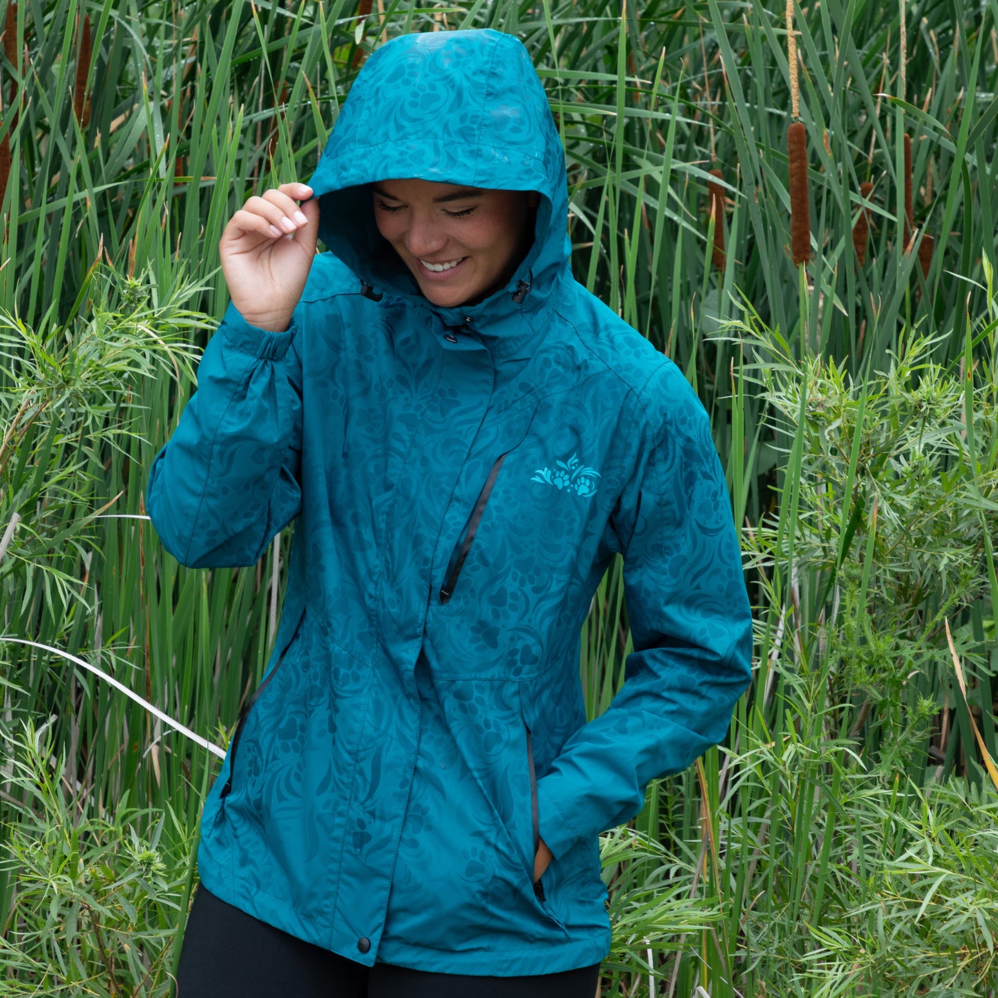 Person wearing a blue raincoat standing in tall green grass.