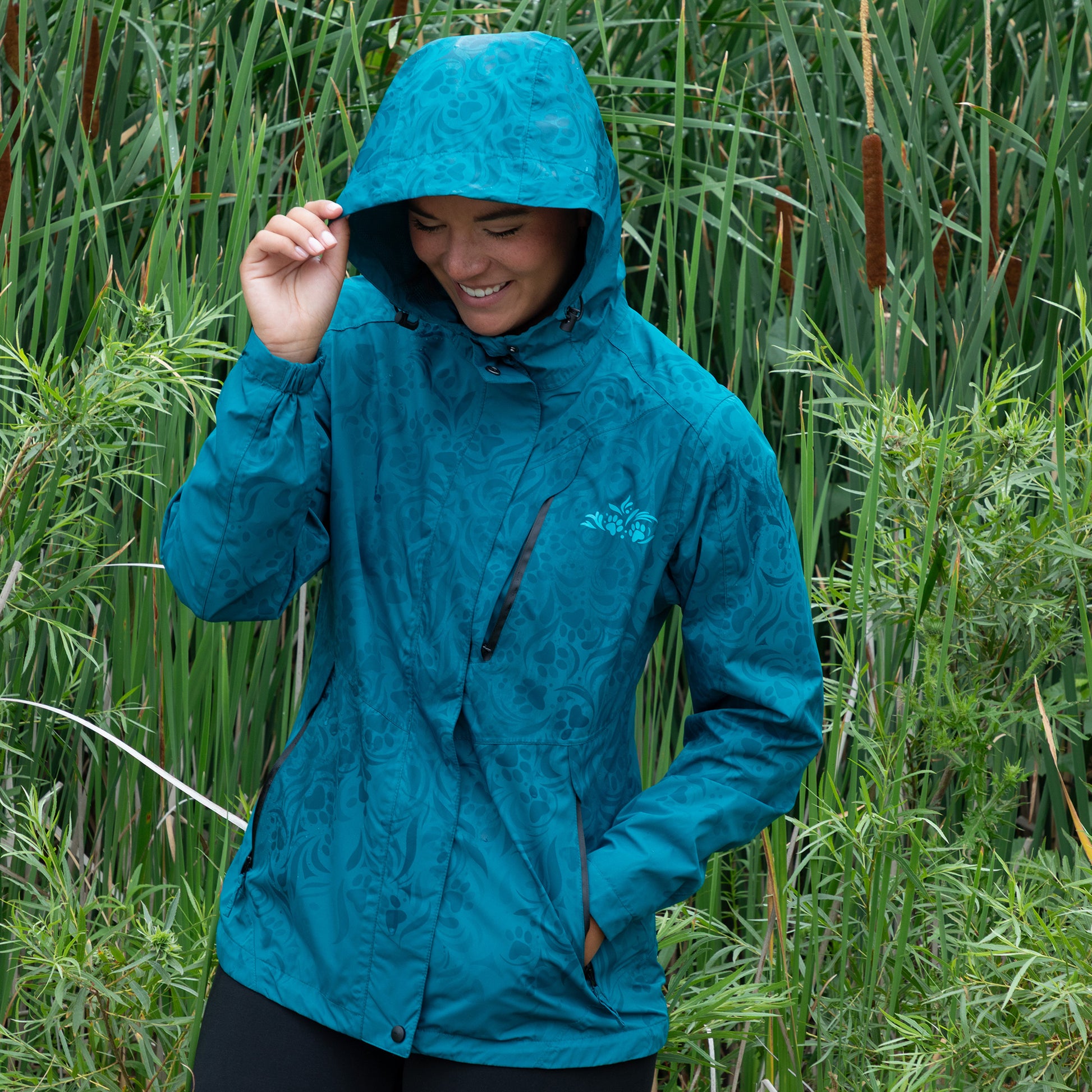 Person wearing a blue raincoat standing in tall green grass.