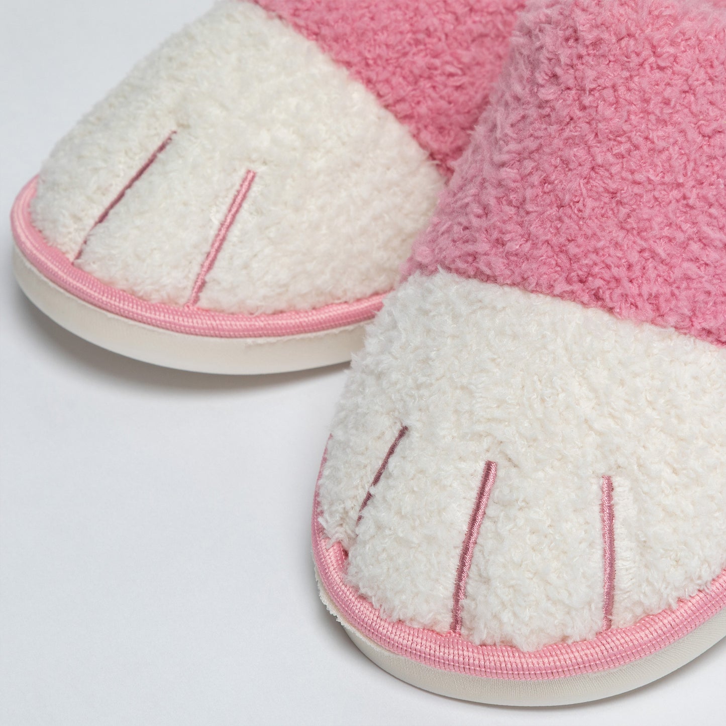 Pair of pink and white slippers on a light gray background