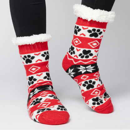 model wearing Pair of red, black white Sherpa Fleece Lined Paw Print Cabin Slipper Socks with sherpa trim on a light gray background alpine fair isle paws red 
