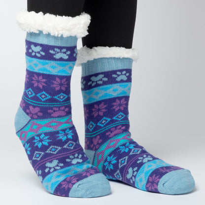 model wearing Pair of blue and purple Sherpa Fleece Lined Paw Print Cabin Slipper Socks with sherpa trim  on a light gray background arctic paws pattern