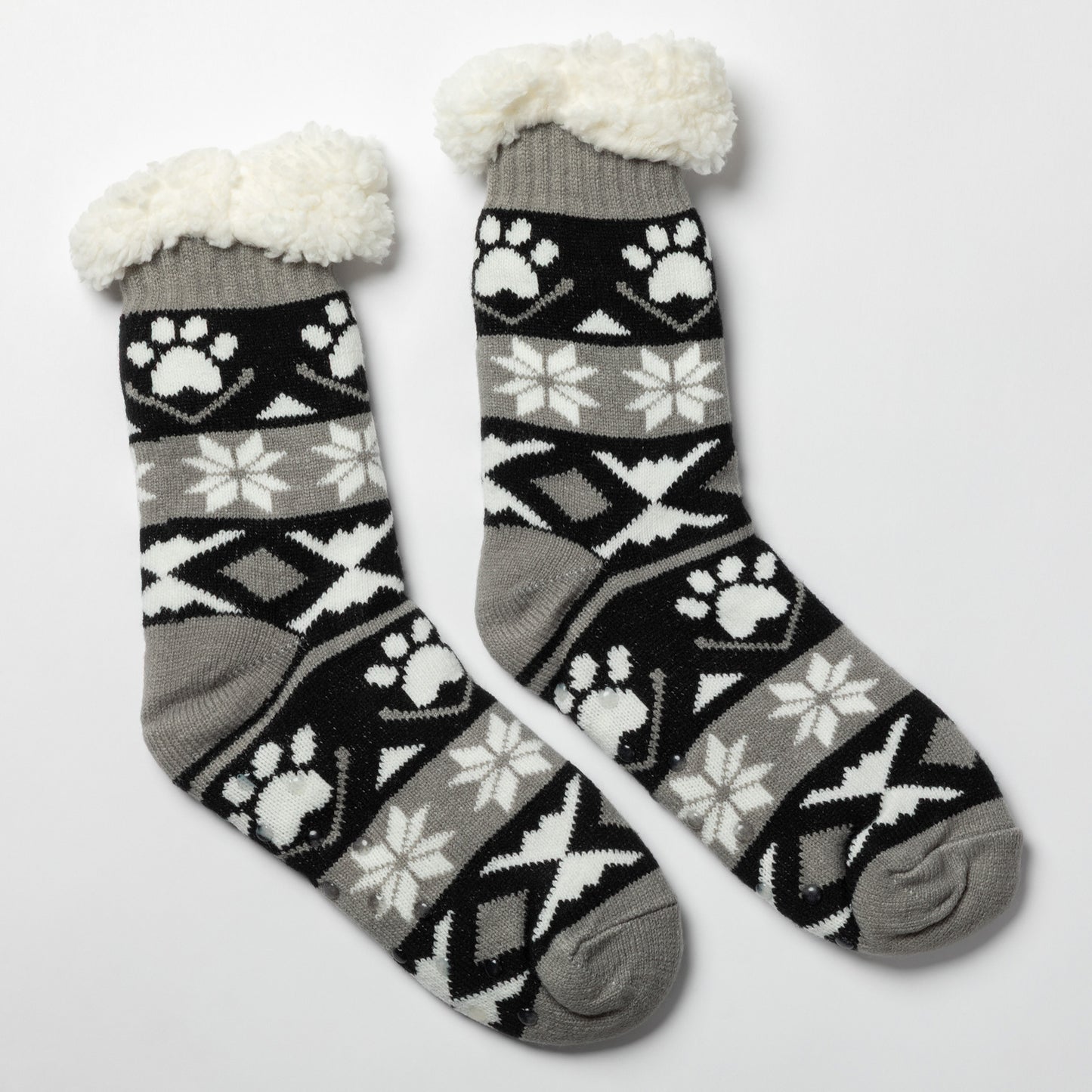 Pair of gray, black white Sherpa Fleece Lined Paw Print Cabin Slipper Socks with sherpa trim on a light gray background alpine fair isle paws black