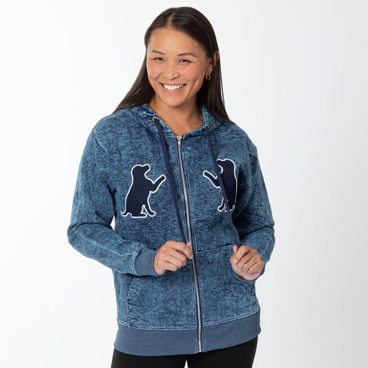 Woman wearing a blue hoodie with dog silhouette embroidered designs on a white background.