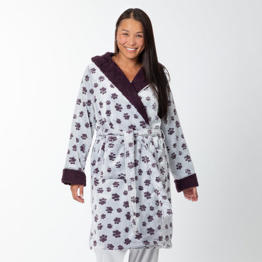 Woman wearing a gray fleece robe with purple paw prints all over, with a sherpa fleece collar and cuffs against a white background.