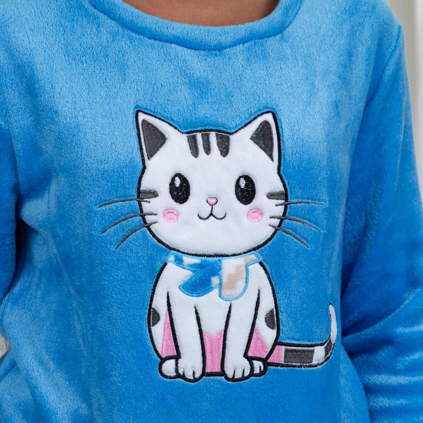 A woman wearing a blue long-sleeve top with an embroidered cute cat design in plush super cozy fabric, in blue cat design